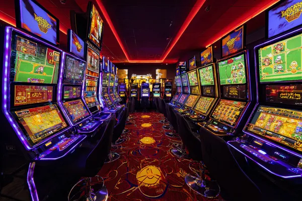 A woman smiling by bright slot machines showing lucky symbols, showcasing the exciting slot offerings at T9999.